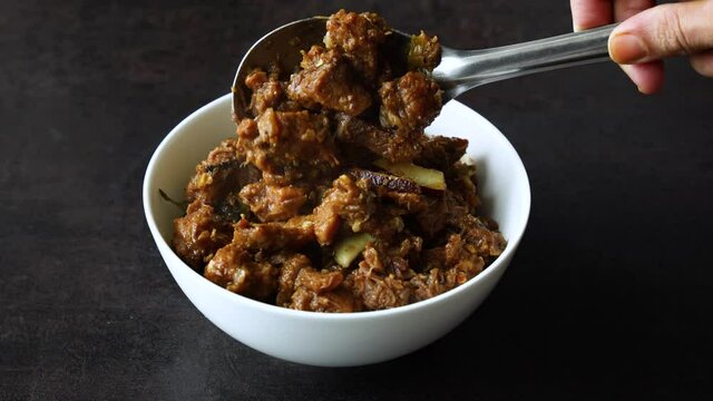 Traditional homemade Mutton curry from Asian cuisine. Chukhandar gosht  woman hand serving spicy meat beef curry 4K video footage mutton roast Indian spices. side dish Ghee rice Appam Parotta Puttu
