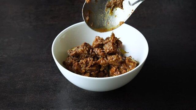 Traditional homemade Mutton curry from Asian cuisine. Chukhandar gosht  woman hand serving spicy meat beef curry 4K video footage mutton roast Indian spices. side dish Ghee rice Appam Parotta Puttu