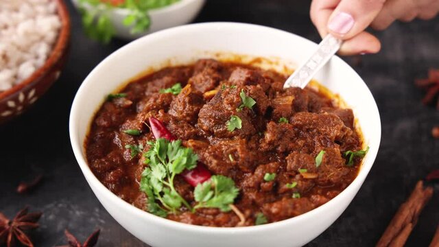 Traditional homemade Mutton curry from Asian cuisine. Chukhandar gosht  woman hand serving spicy meat beef curry 4K video footage mutton roast Indian spices. side dish Ghee rice Appam Parotta Puttu