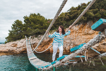 woman crossing suspension bridge sea on background