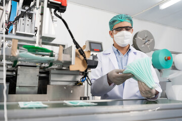 male factory worker are producing medical face masks, counting and checking of quality from machine