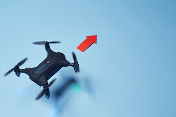 Aerial top down view on isolated drone copter with spinning propellers flying in the red arrow...