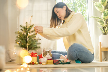 asian woman smile and happy during decorate christmas tree with her cat