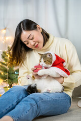 asian woman smile and happy during play and clothing red santa blanket to her cat