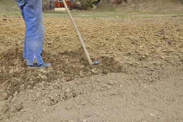 A farmer cultivates shoveled soil before planting in the spring in a traditional village