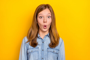 Photo of impressed cute small blond girl look camera wear jeans shirt isolated on vibrant yellow color background