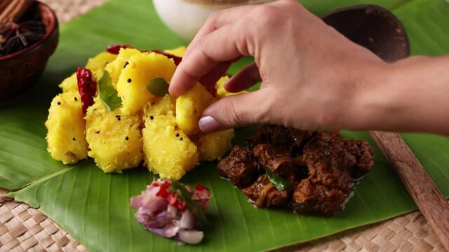 Cooked tapioca Cassava root Kappa with spicy meat beef pork curry Mandioca Aipim Indian food woman eating with hand banana leaf 4K video footage South Indian food Asian cuisine Kerala India Sri Lanka