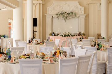 Decorated wedding hall, served tables and dishes, round tables and a bright hall.
