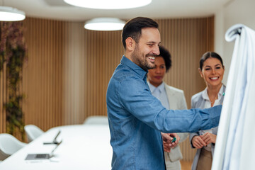 Happy caucasian man, helping his female colleagues with their work problems.