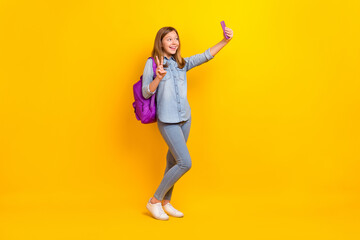 Full body photo of nice teenager girl do selfie wear bag jeans shirt shoes isolated on yellow background