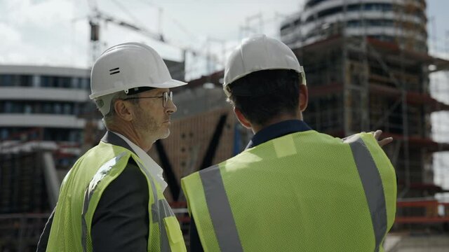 Two builders controlling working process on construction site