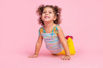 Portrait of attractive cheerful funny wavy-haired girl lying on floor having fun crawling isolated...
