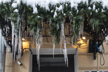 Green branches of fir with cones and toys, icicles hang above the entrance to the door