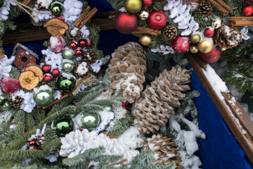Christmas wreath of fir branches with decorations hanging on the wall of the house