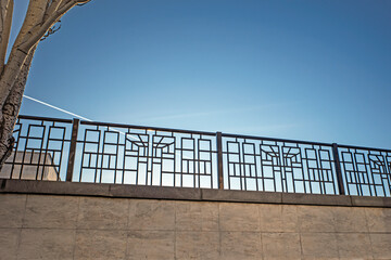 View through the fence to the blue sky with a flying plane on a sunny winter day