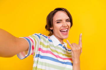 Photo of funny young brunette lady do selfie show rock wear white t-shirt isolated on yellow color...