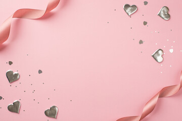 Top view photo of st valentine's day decorations curly silk ribbon silver hearts sequins and heart shaped confetti on isolated pastel pink background with copyspace in the middle