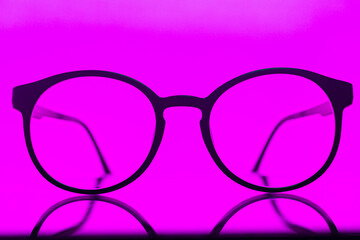 Round eyeglasses on a pink background. Fashionable round computer glasses.