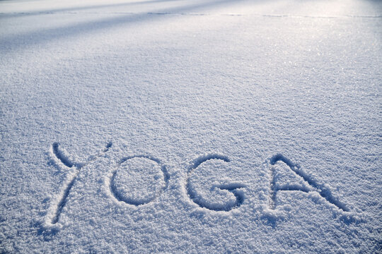 The word yoga is written in the snow. Winter yoga in the morning sun. a minimalist picture of Zen Buddhism. Peace and tranquility.