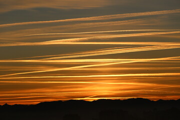 Dawn sky with aircraft vapour trails criss crossing showing busy aircraft activity in December 2021...