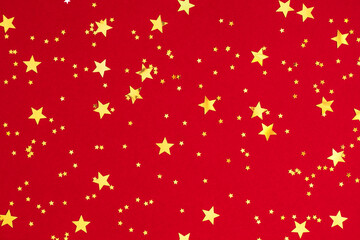 Fototapeta na wymiar Gold stars on red background. Festive red background with gold stars confetti. Flat lay, top view, copy space