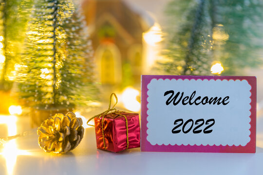 Welcome 2022 writing on greeting card with small house and lights background