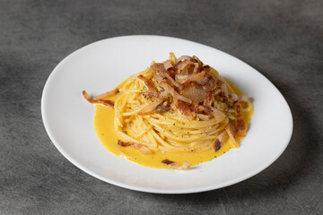 Dish of Spaghetti alla Carbonara, typical italian recipe of pasta with guanciale, egg and pecorino romano cheese. Soft light, angle view. Traditional italian cuisine. Pasta alla carbonara