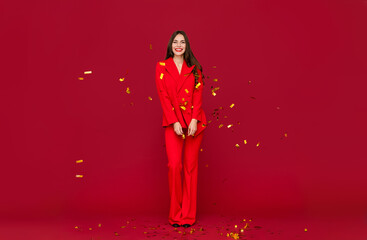 attractive woman celebrating Christmas on red background in confetti