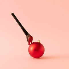 Creative idea made of makeup brush with red glitter slime and Christmas red ball on pink...