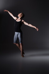 elegant man gesturing while performing ballet dance on black