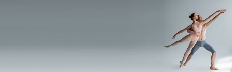 full length of couple performing ballet dance on dark grey, banner