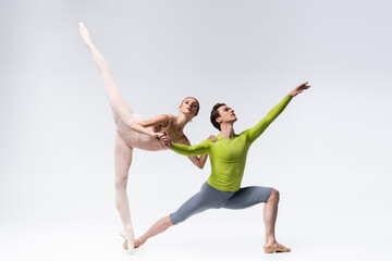 full length of flexible young ballet dancers on grey