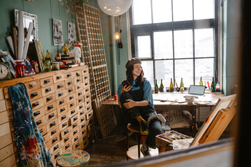 Young woman using mobile phone while working in her studio