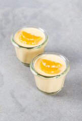 Tangerine cream pudding in glass on a light gray background