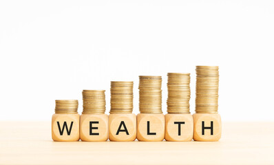 Wealth concept. Wooden blocks with text and rising stacked coins. Copy space