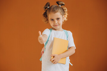 Little school girl with notebook and rucksack isolated in background