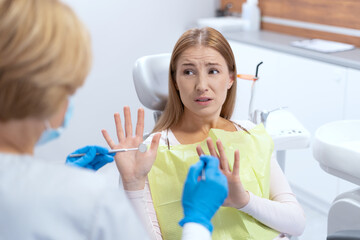 Funky woman refusing of teeth treatment during dentist visit