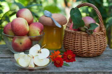 apples, honey and flowers on wooden table in garden
