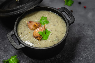 Creamy roasted mushroom soup in cast iron pot. Copy space.