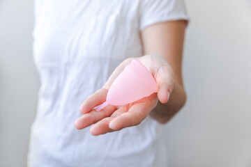 Woman hand holding pink menstrual cup isolated on white background. Woman modern alternative eco gynecological hygiene in menstruation period. Container for blood in girl hand