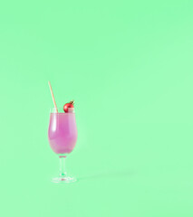 A cocktail decorated with a red Christmas ball on a green background. Minimal creative idea. Party concept.