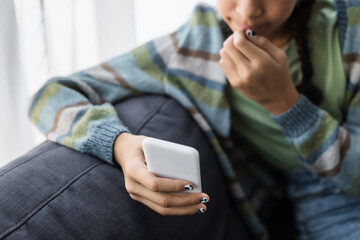 cropped view of blurred african american teenage kid chatting on cellphone at home