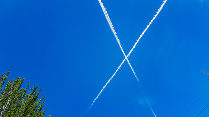 white lines of aircraft passing in the blue sky