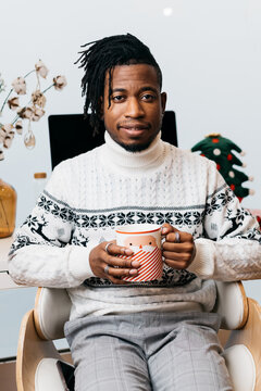 A man holding a mug while sitting on a chair