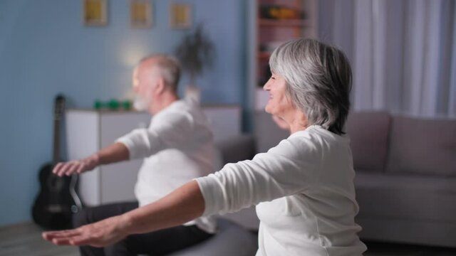 sports elderly family, happy woman and man doing fitball workout in home, retirement couple with raised arms turns left and right