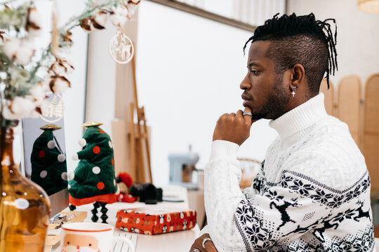 Man wearing a sweater working around Christmas ornaments