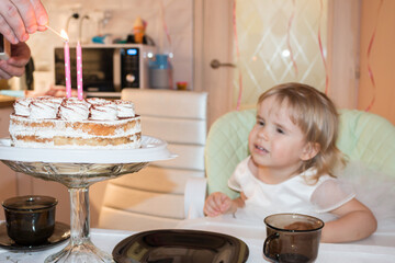 Birthday of a two-year-old girl, an appetizing cake with two burning candles
