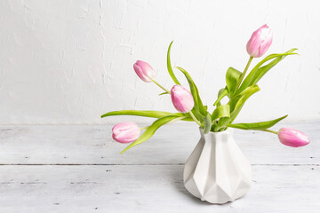 Bouquet of gentle pink tulips in ceramic vase on white background