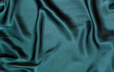 Dark green silk draped fabric. Satin textile texture background	