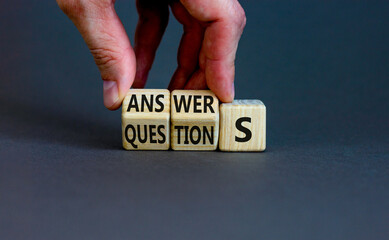 Q and A questions and answers symbol. Businessman turns wooden cubes and changes the word questions to answers. Beautiful grey background, copy space. Business Q and A questions and answers concept.